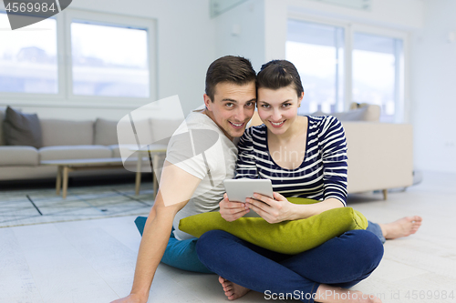 Image of Young Couple using digital tablet on the floor