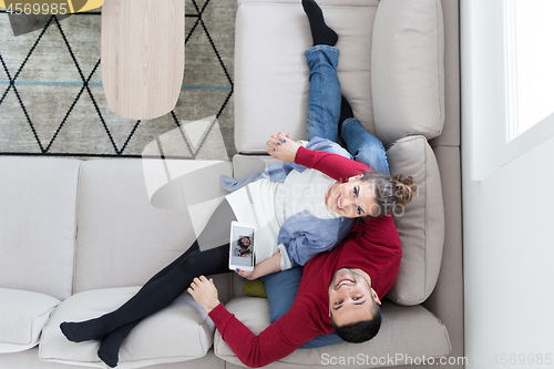 Image of couple relaxing at  home with tablet computers