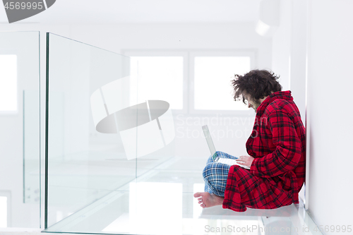 Image of young freelancer in bathrobe working from home