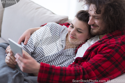 Image of couple relaxing at  home with tablet computers