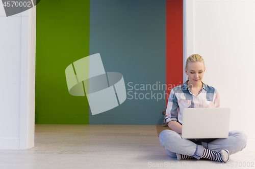 Image of young woman using laptop computer on the floor