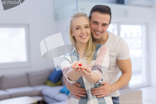 Image of couple showing small red house in hands