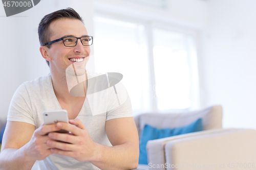 Image of young man using a mobile phone  at home