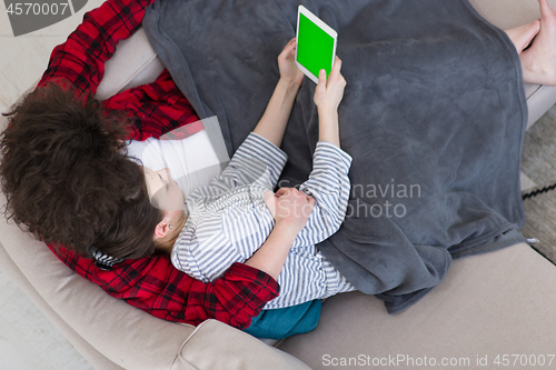 Image of couple relaxing at  home with tablet computers