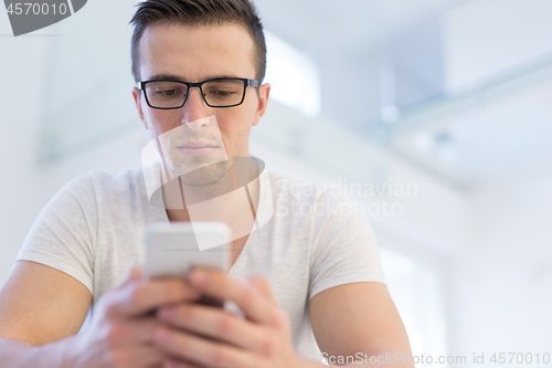 Image of young man using a mobile phone  at home