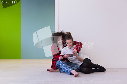 Image of Young Couple using digital tablet on the floor