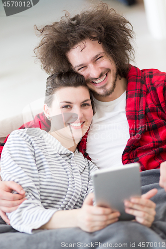 Image of couple relaxing at  home with tablet computers