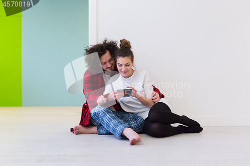 Image of Young Couple using digital tablet on the floor