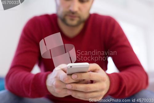 Image of young man using a mobile phone  at home