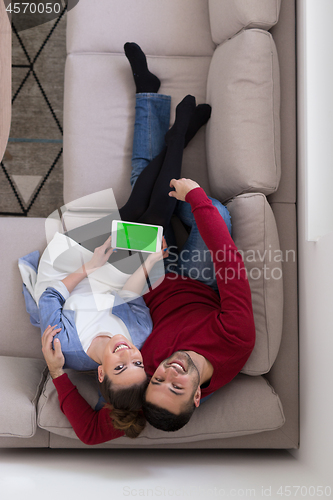 Image of couple relaxing at  home with tablet computers