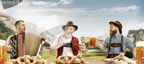 Image of Germany, Bavaria, Upper Bavaria, men with beer dressed in traditional Austrian or Bavarian costume