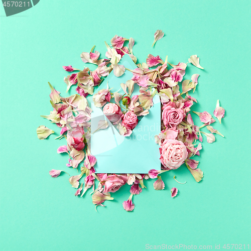 Image of Card for congratulation with envelope and fresh flowers on a light turquoise background.