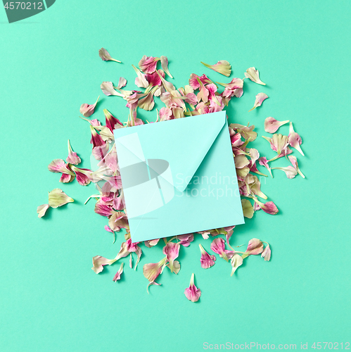 Image of Mock up craft envelope with floral petals on a turquoisebackground.