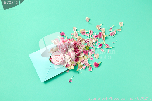 Image of Fresh pink roses in handmade envelope on a turquoise background.