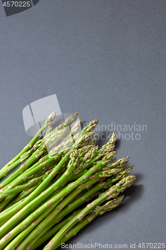 Image of Pile of green organic asparagus on a grey background.