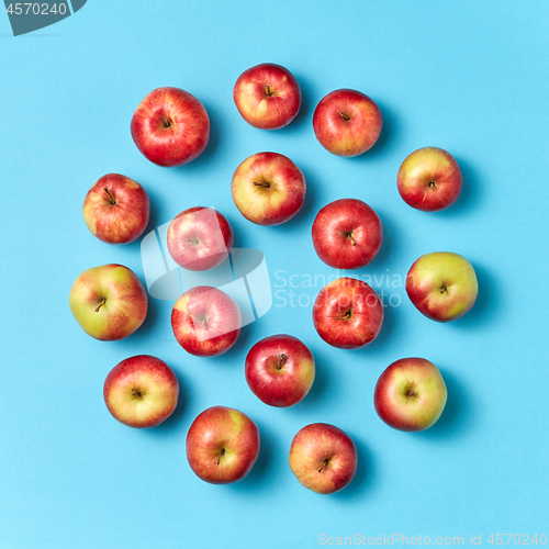 Image of Organic apples round pattern on a blue background.