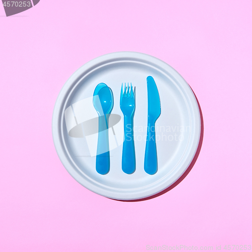Image of Served place with eating plastic utensil on a pastel pink background.