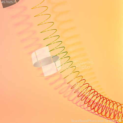 Image of Stretching rainbow plastic spring toy with shadows.