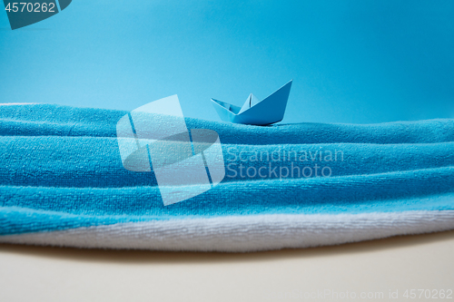 Image of Waves of blue sea made from beach towel with paper boat.