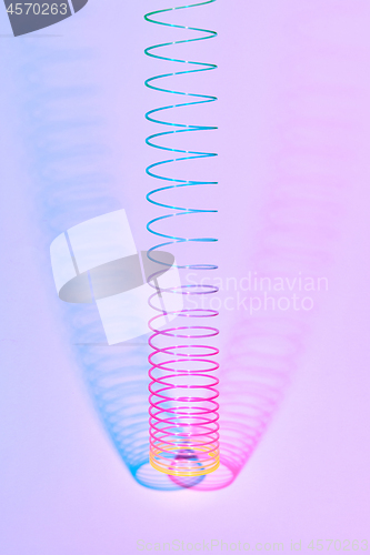 Image of Vertical rainbow plastic slinky toy with two color shadows.