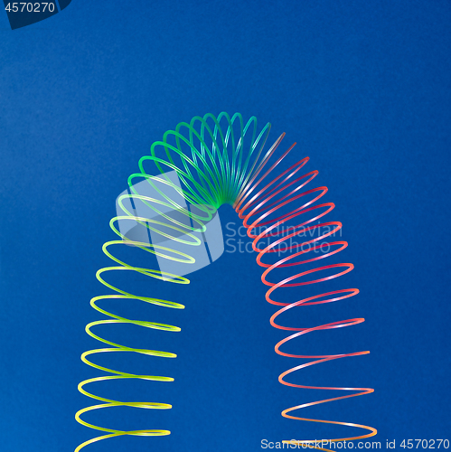 Image of Flexible plastic rainbow spring on a blue background.