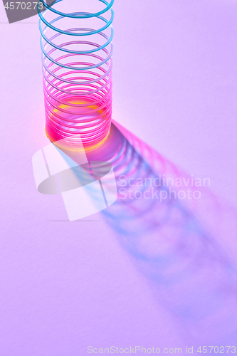 Image of Stretching colored plastic slinky toy with shadows.