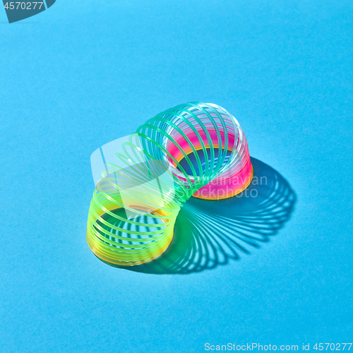 Image of Toy plastic rainbow slinky with shadows on blue.