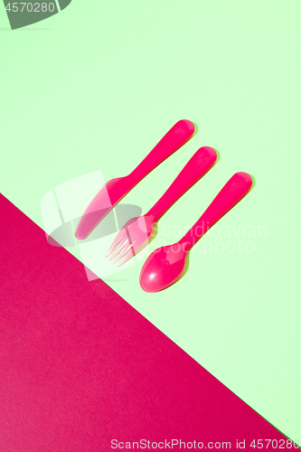 Image of Dining set from colored plastic cutlery on a duotone background.