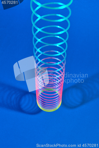 Image of Vertical stretching plastic slinky toy with two shadows.