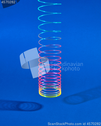 Image of Hunging colorful plastic toy spiral with two shadows.