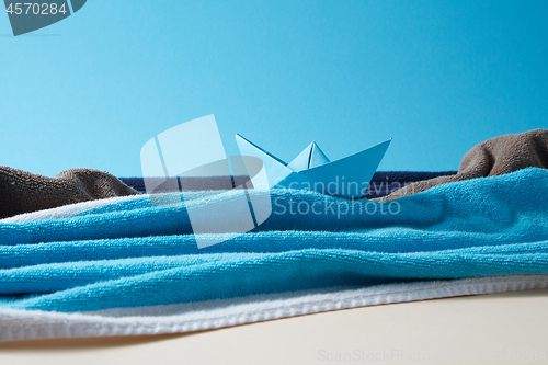 Image of Seascape made from terry towels with paper boat and rocks.