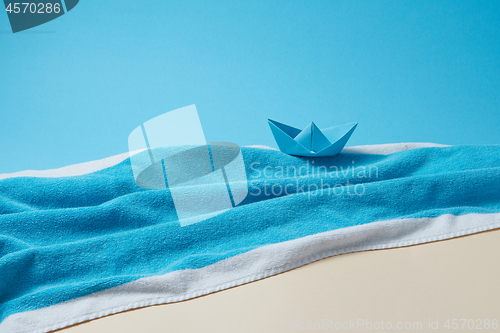 Image of Paper boat on a terry blue towel as a seascape.