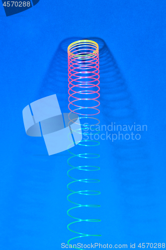 Image of Hunging rainbow plastic slinky with two shadows.