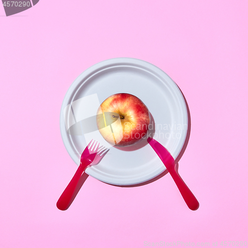 Image of Fresh apple on a plate served with plastic knife and fork