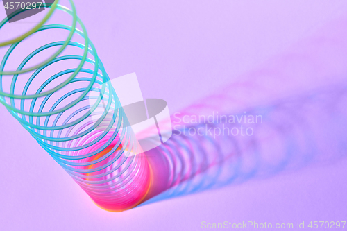 Image of Rainbow plastic slinky toy with duotone shadows.