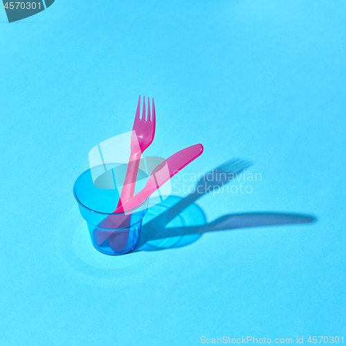 Image of Served place with eating plastic utensil and glass with shadows.