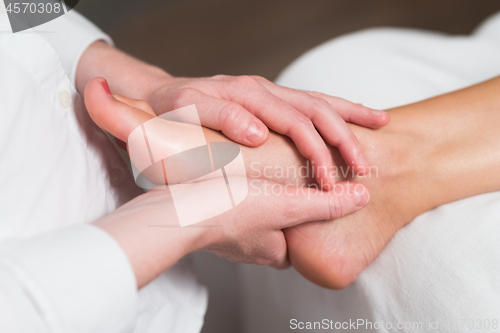 Image of Professional female masseur giving reflexology massage to woman foot