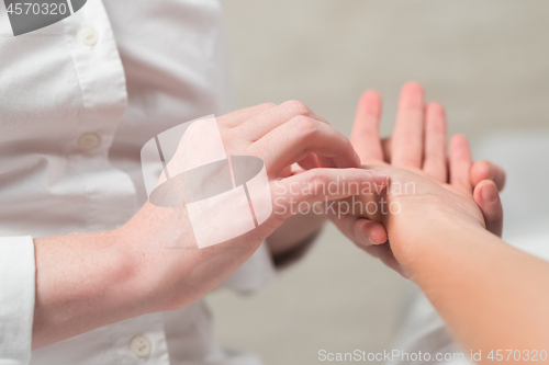 Image of Professional female masseur giving reflexology massage to woman palm