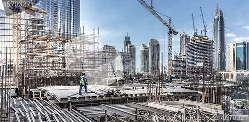 Image of Laborers working on modern constraction site works in Dubai. Fast urban development consept