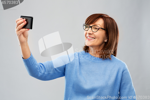 Image of senior woman taking selfie by smartphone