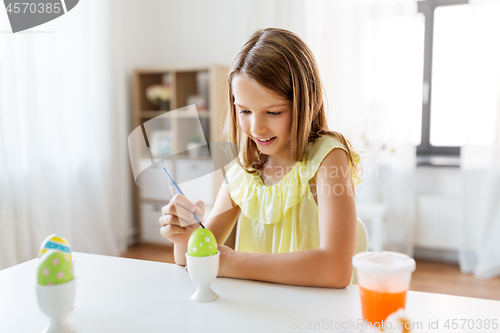 Image of happy girl coloring easter eggs at home