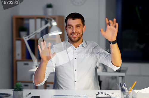 Image of businessman using gestures at night office