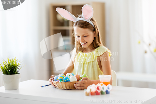 Image of happy girl with colored easter eggs at home