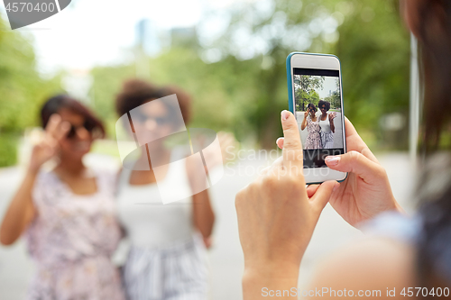 Image of woman photographing her friends in summer park