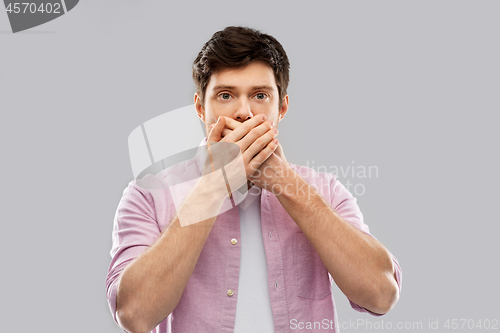 Image of shocked young man covering his mouth by hands