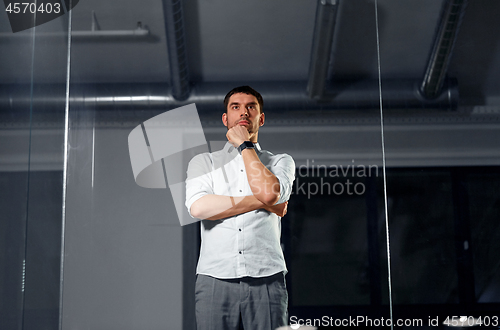 Image of businessman looking at glass wall at night office