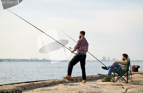 Image of happy friends with fishing rods on pier