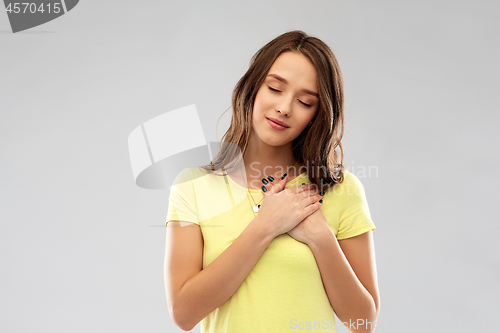 Image of smiling teenage girl holding hands on heart