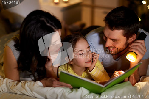 Image of happy family reading book in bed at night at home