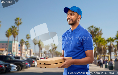 Image of happy indian delivery man with pizza boxes in blue